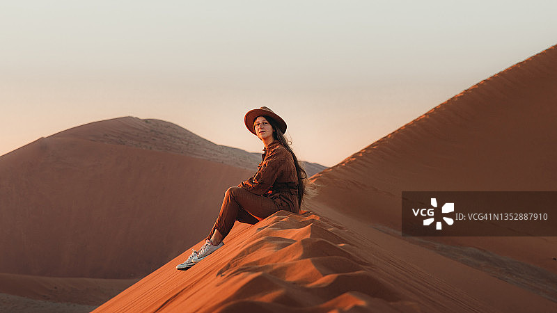 女游客在纳米布沙漠的沙丘上欣赏日出美景图片素材