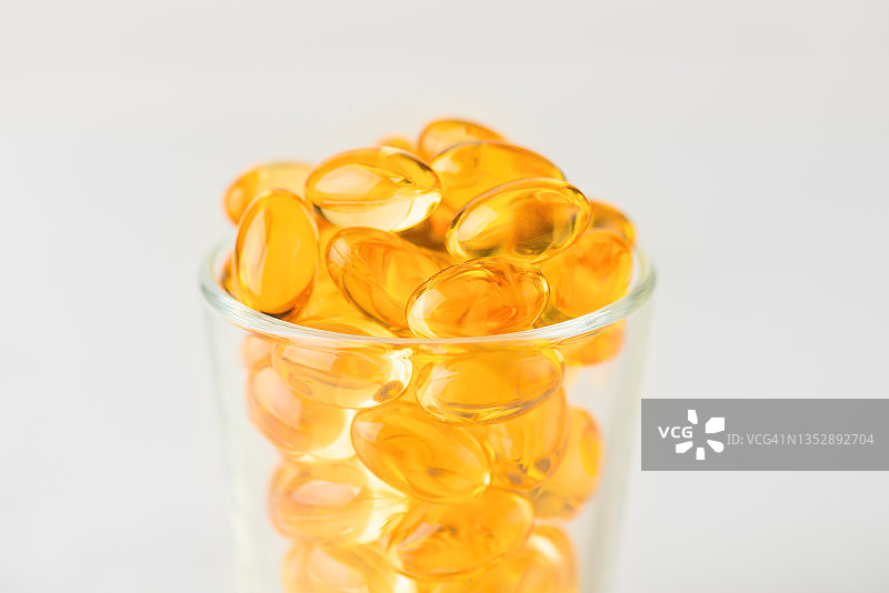 白色背景玻璃瓶中的Ω-3鱼油胶囊图片素材