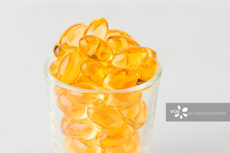 白色背景玻璃瓶中的Ω-3鱼油胶囊图片素材