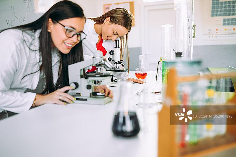 女人在实验室教室里用显微镜观察图片素材