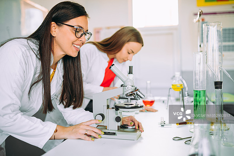 女人在实验室教室里用显微镜观察图片素材