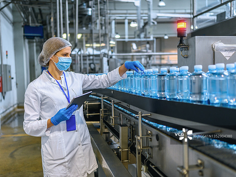 瓶装工厂的技术人员在装运前检查水瓶。图片素材