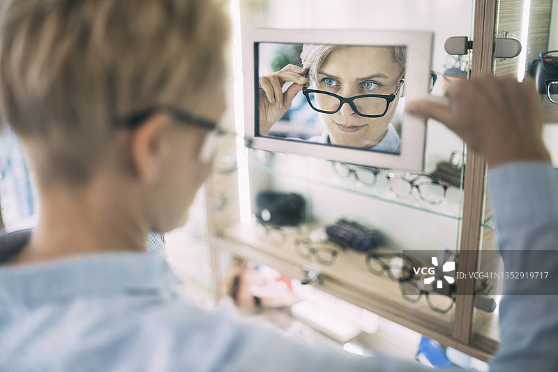 年轻女人照镜子看新眼镜特写图片素材