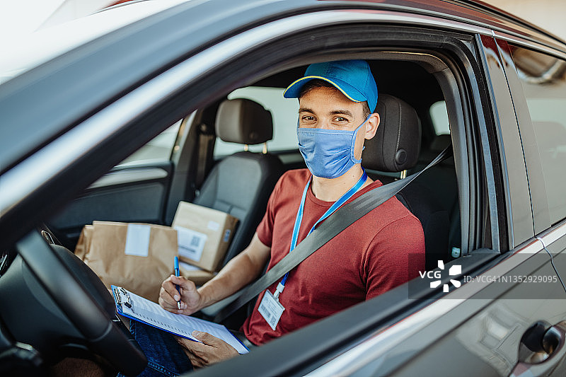 在装有包裹的车辆中戴着口罩的配送员图片素材