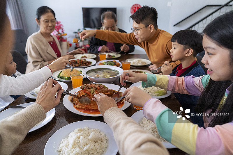 中国新年团圆饭：家人在餐桌旁享用传统菜肴图片素材
