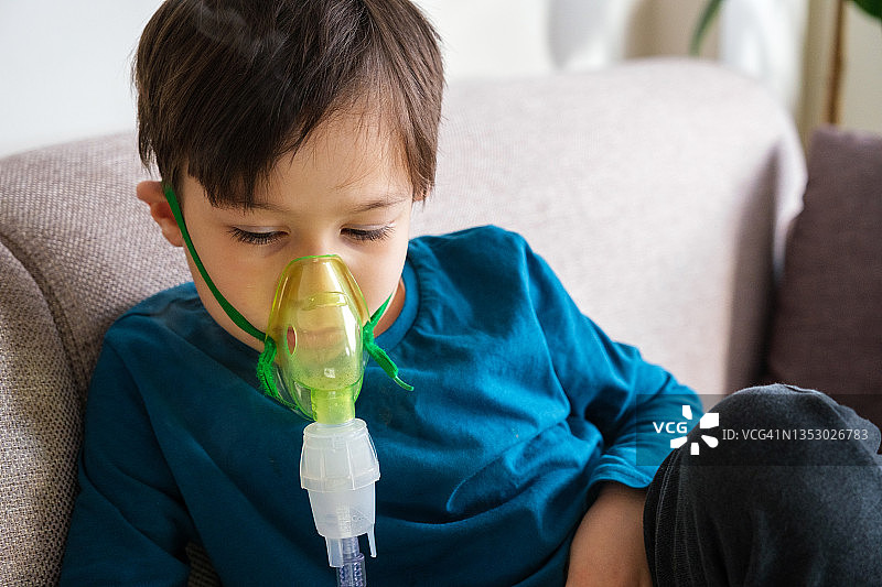 哮喘男孩坐在家中的沙发上图片素材