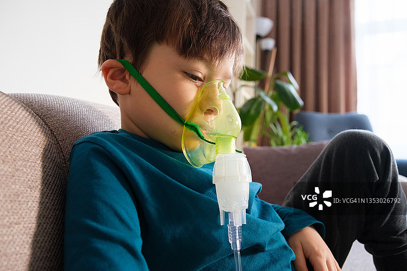 哮喘男孩坐在家中的沙发上图片素材