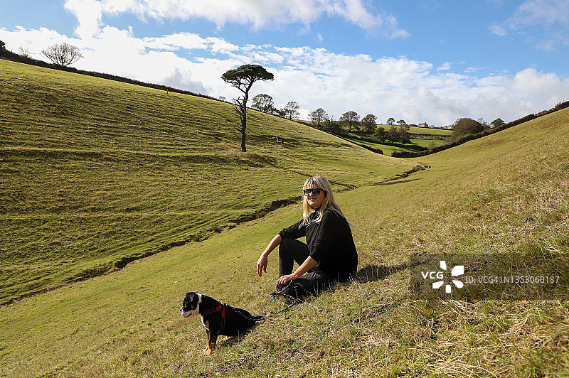 女士和狗一起坐在山上图片素材