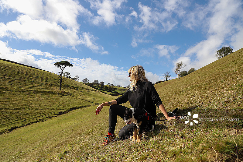 女士和狗一起坐在山上图片素材