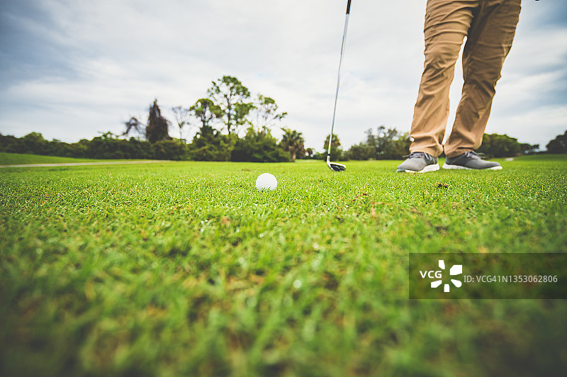 球道上的高尔夫球特写：高尔夫球手站在旁边，无法辨认图片素材