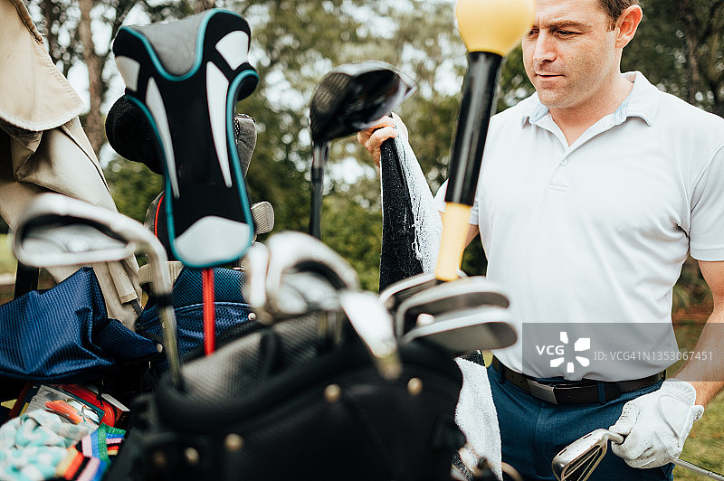 男人从高尔夫球包中选择他的高尔夫球杆图片素材