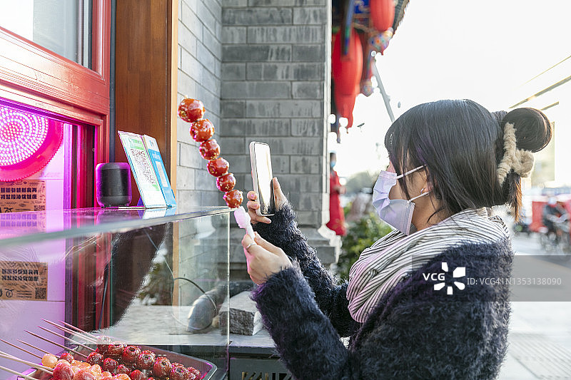 年轻女人用手机购买街头小吃图片素材