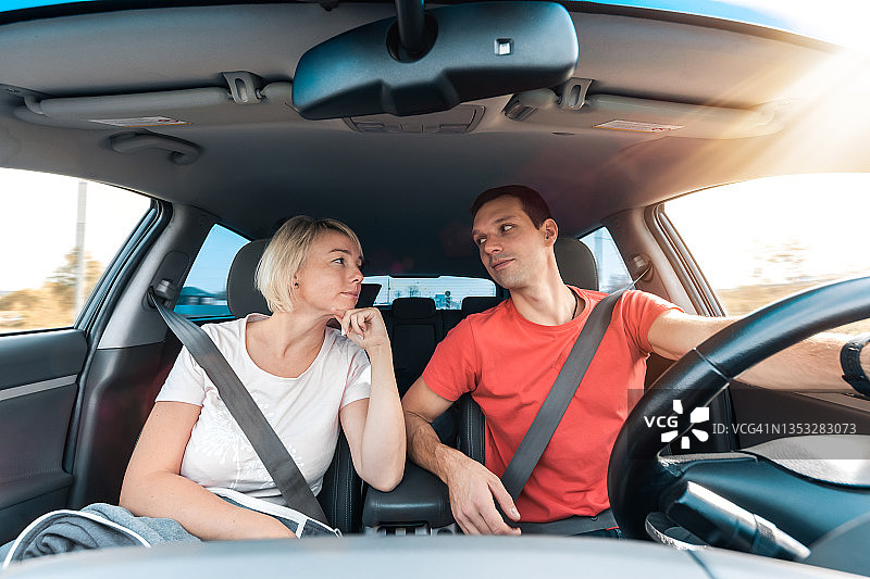 系着安全带，驾车时互相对视的年轻男女图片素材