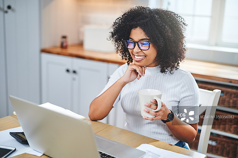 年轻女人在家用笔记本电脑工作喝咖啡的照片图片素材