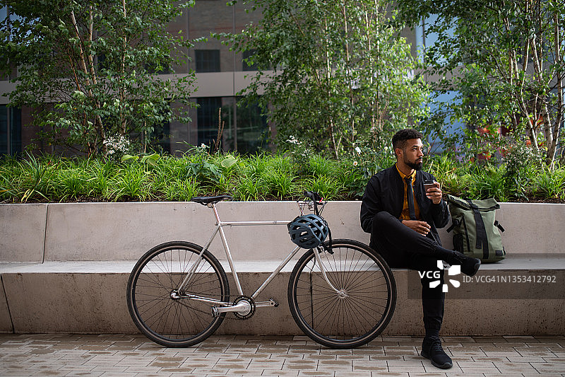 年轻人骑自行车通勤，坐在城市户外长椅上喝咖啡图片素材