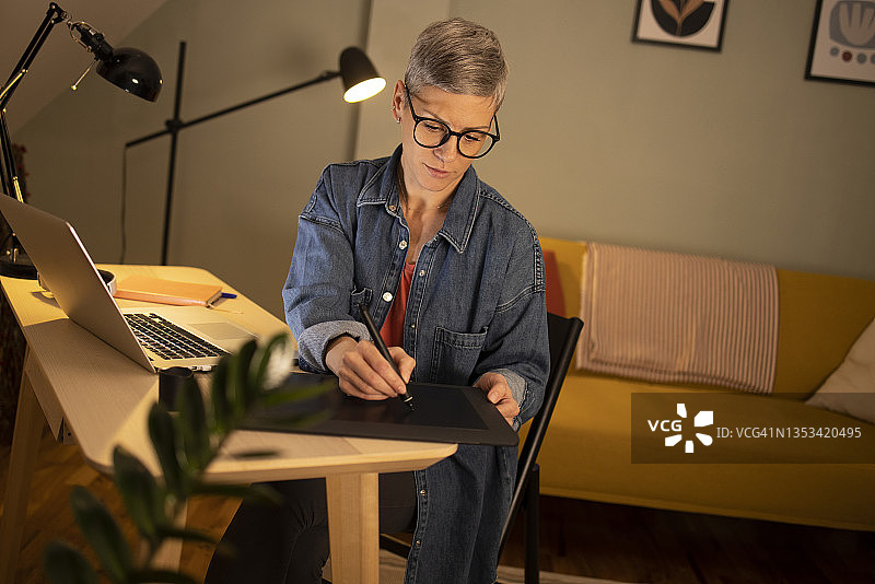 使用绘图板工作的中年妇女肖像图片素材