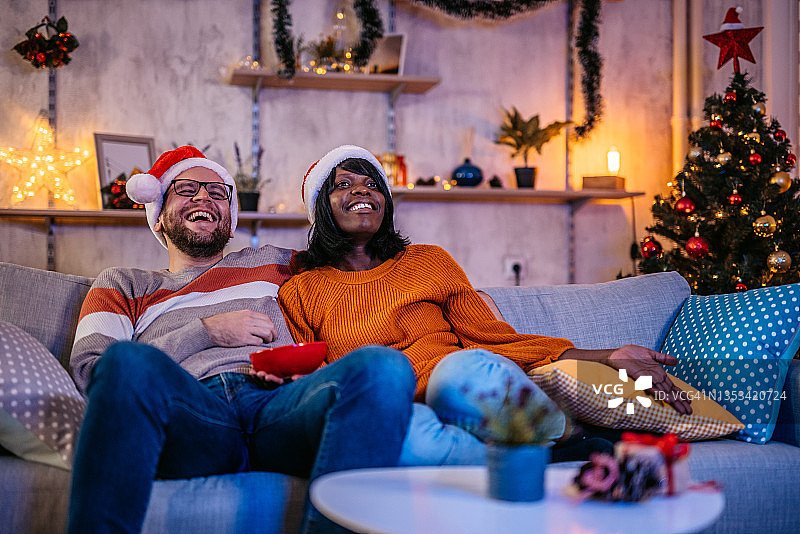 年轻夫妇在圣诞节期间在家看电视图片素材