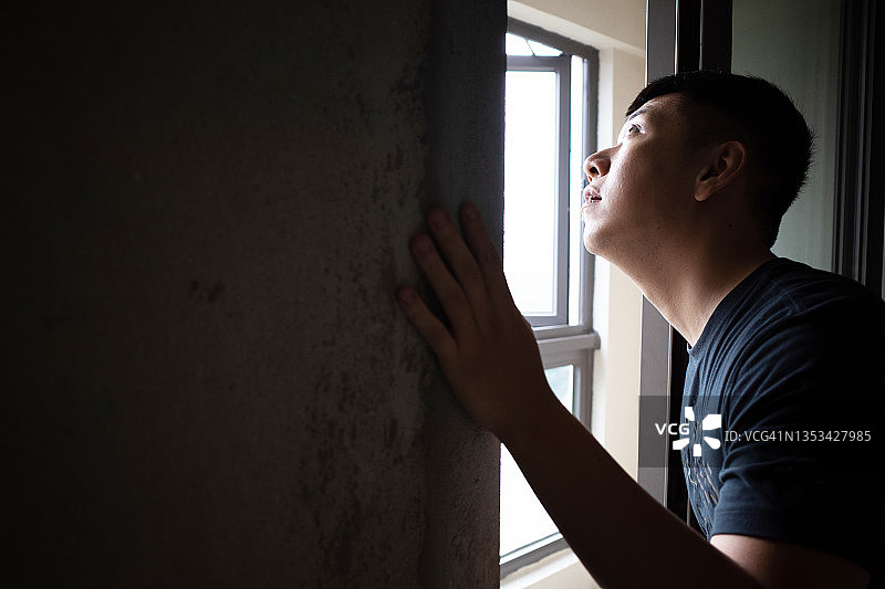 年轻男人在毛坯房里向窗外看图片素材