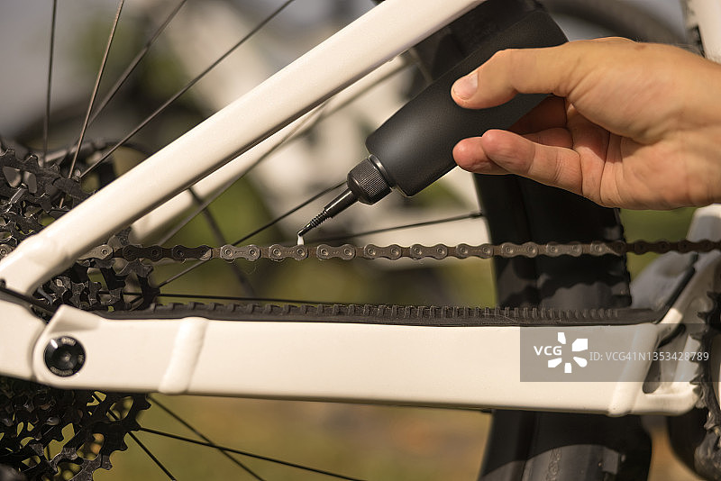 男人手部在自行车链条上涂油图片素材