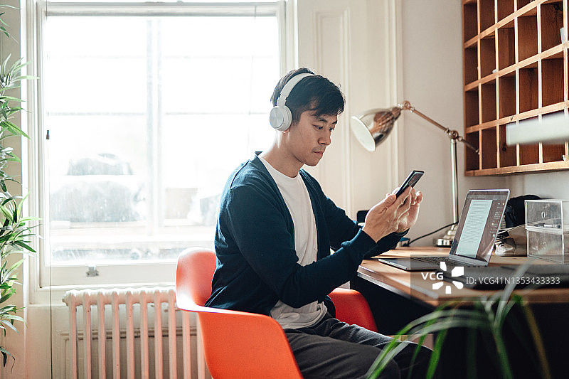 在家用笔记本电脑和智能手机工作的自信年轻职业人士图片素材