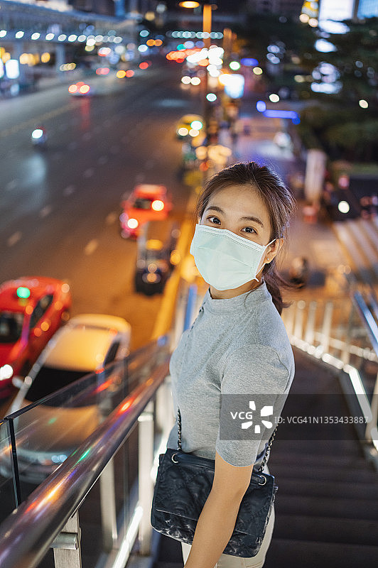 在泰国曼谷暹罗中心佩戴口罩微笑看向镜头的亚洲Gen Z女商人，在曼谷公共车站等候公共交通图片素材