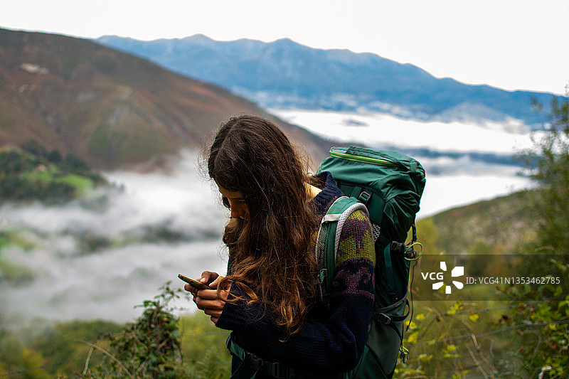 秋季山路，年轻女子看智能手机特写图片素材
