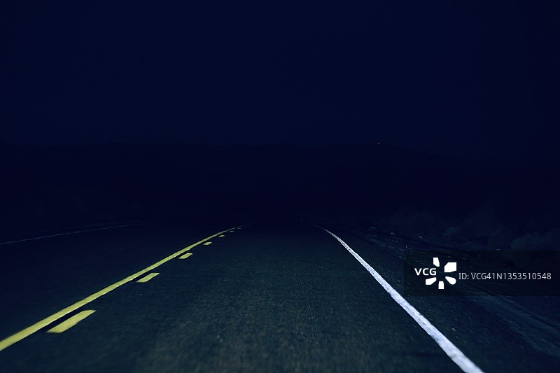 黑色背景上的笔直道路与白色标线图片素材