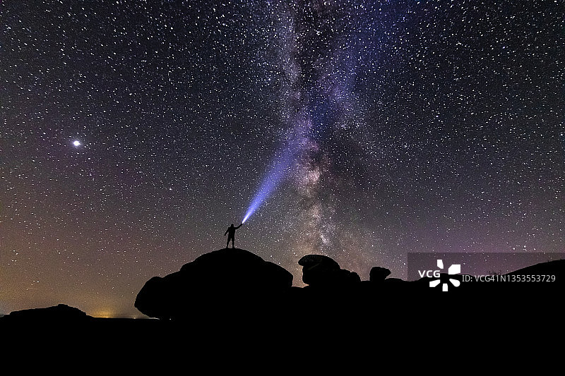 男子夜晚在山顶用手电筒看银河图片素材