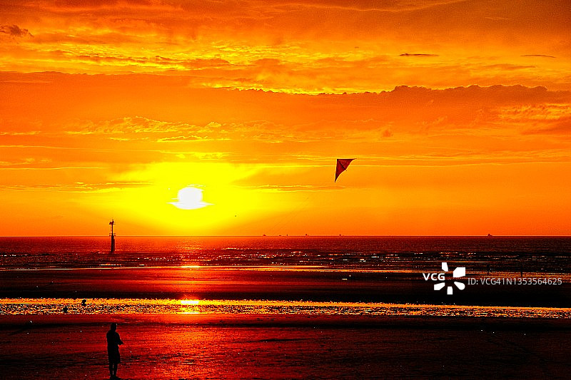 在海边日落时放风筝图片素材