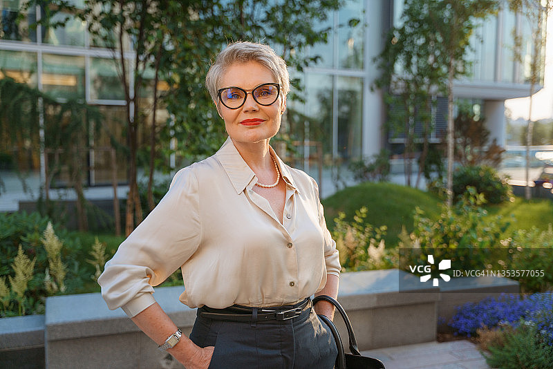 一位微笑的女商人看着镜头，站在商业中心附近的街道上图片素材