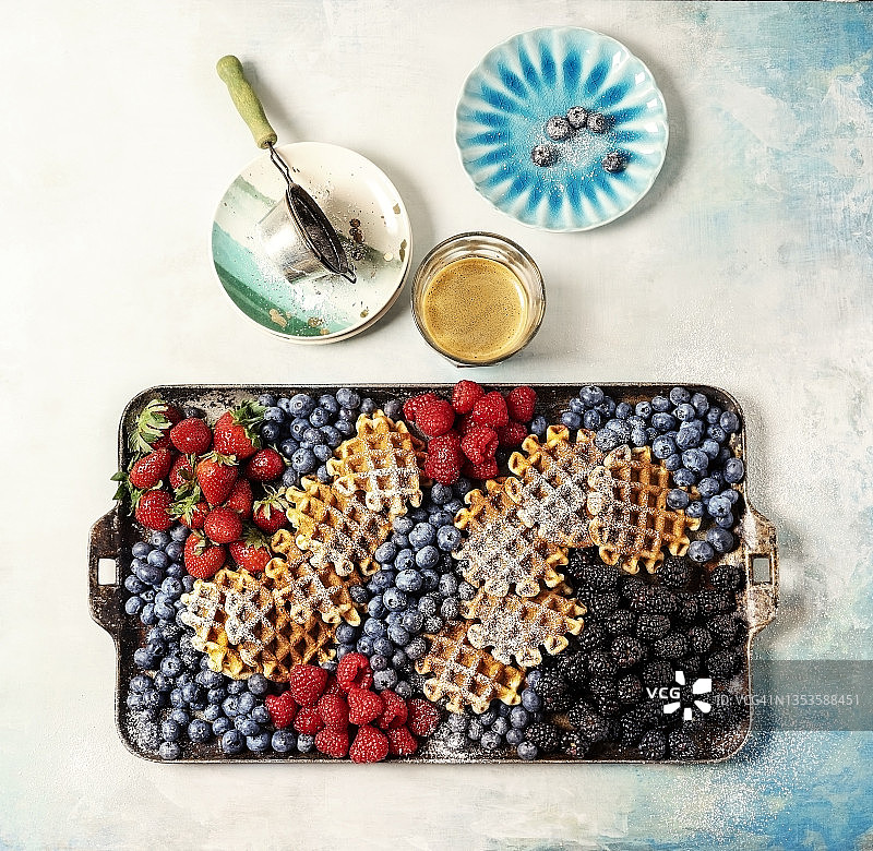 蓝色背景上的华夫饼和浆果早午餐拼盘图片素材