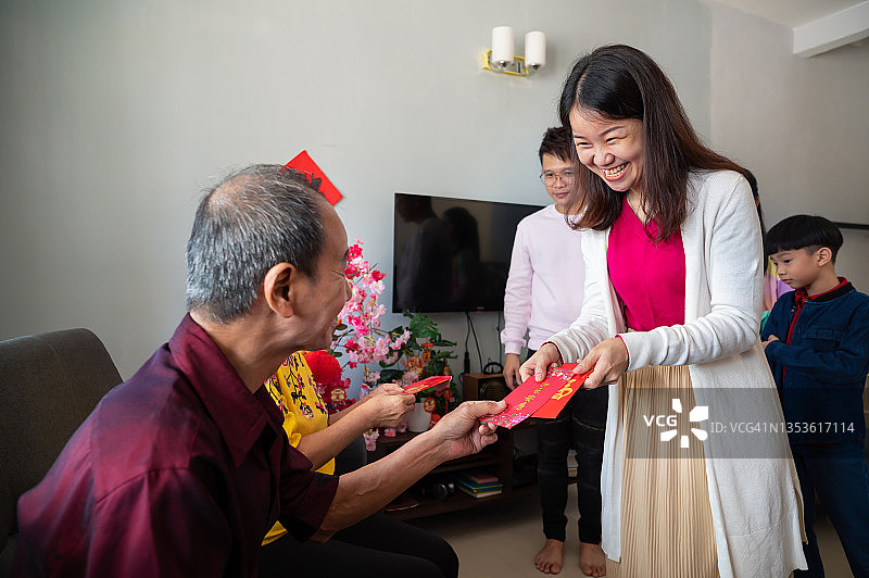 快乐的中国亚洲父母在农历新年第一天在家给孩子们红包图片素材