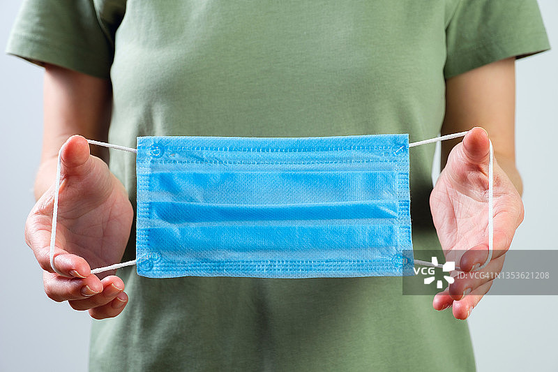 年轻女医务工作者手持口罩，疫情与隔离防护图片素材