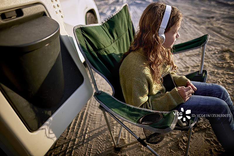 女孩在露营车旁戴耳机听音乐图片素材