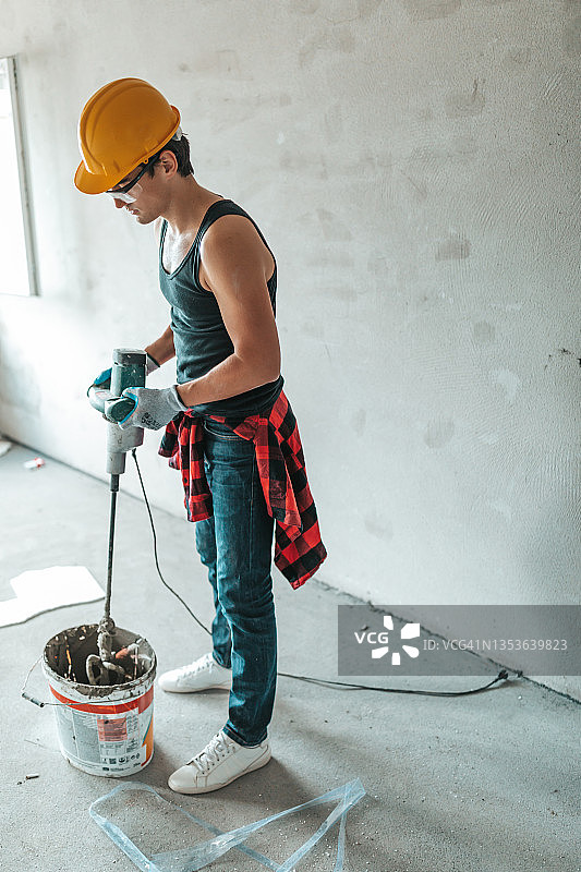 用电动钻在桶中混合瓷砖粘合剂图片素材