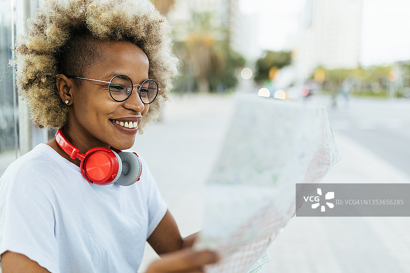 面带微笑的女旅行者在城市中探索时在地图上寻找方向图片素材