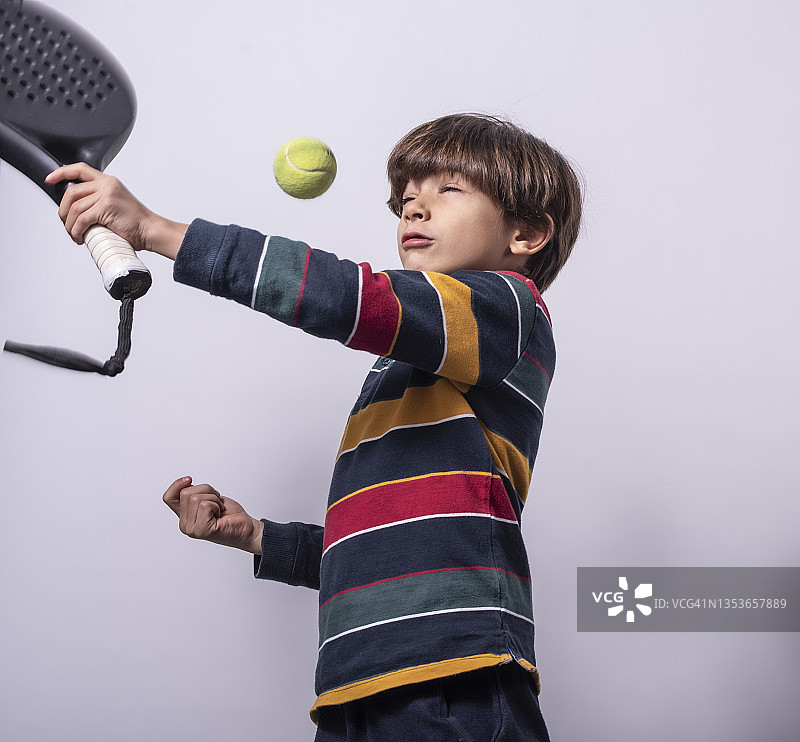 男孩在白色背景的影棚里打板式网球图片素材