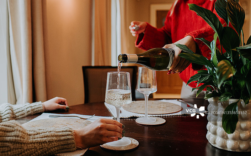 女服务员为坐在桌旁的顾客倒一杯白葡萄酒图片素材