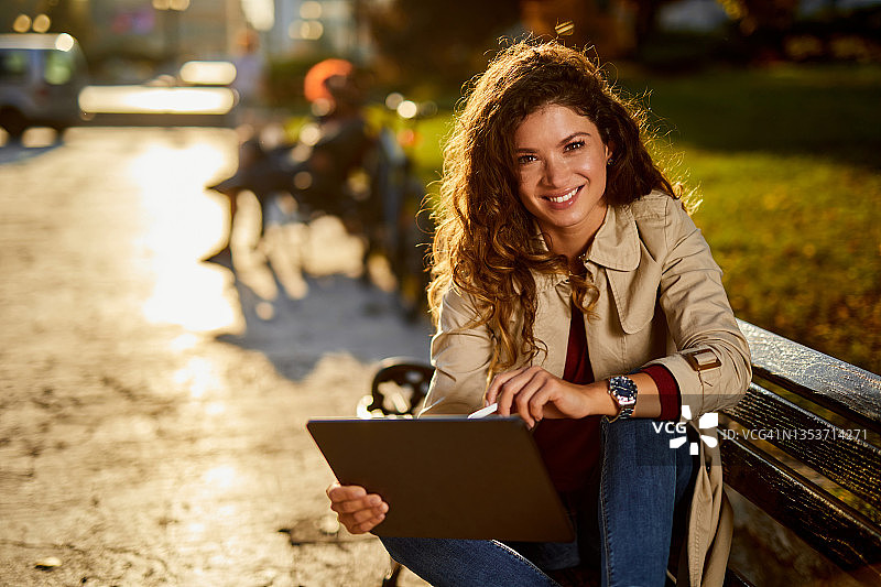 中年女人坐在长凳上使用平板电脑图片素材
