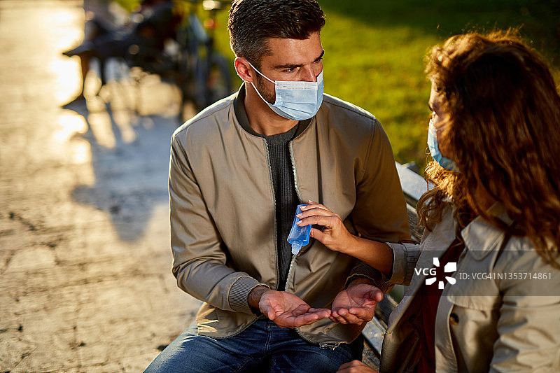 中年夫妇在户外佩戴防护口罩并使用免洗洗手液图片素材