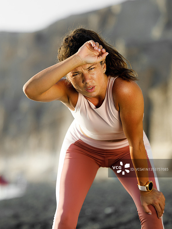 在海滩上气喘吁吁的疲惫女运动员图片素材