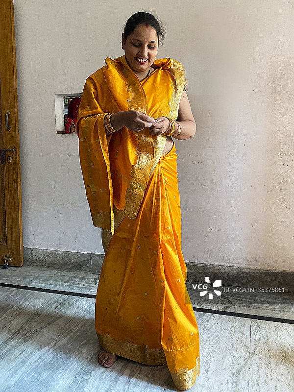 印度教印度妇女穿着传统服装，色彩鲜艳的橙色纱丽，头发分界处戴着辛多，额头上戴着宾迪，重点放在前景上图片素材