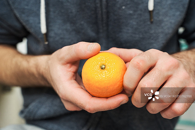 男人手中拿着明亮多汁的橙子的特写图片素材