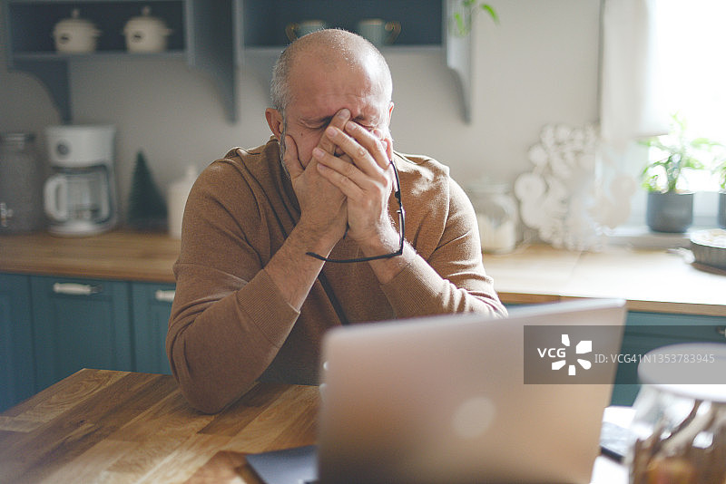 中年男人在舒适的家庭厨房内（笔记本电脑，负面情绪）图片素材