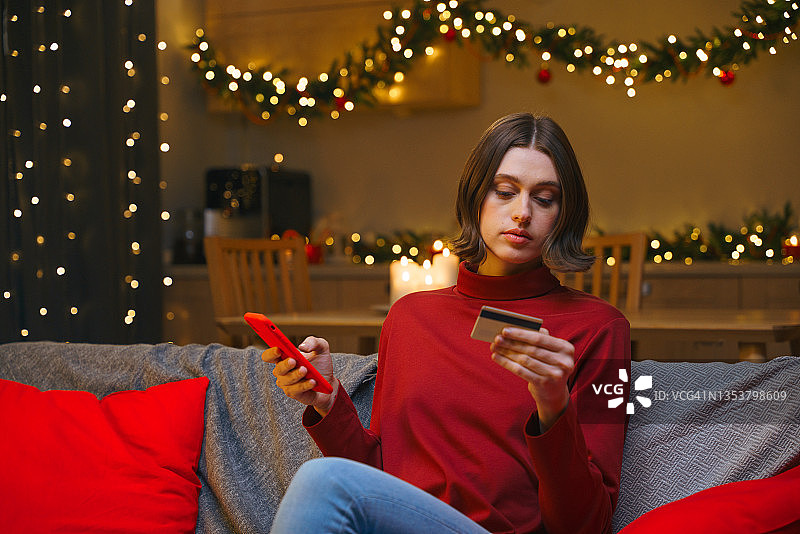 圣诞节夜晚，女子在家用手机网购支付图片素材