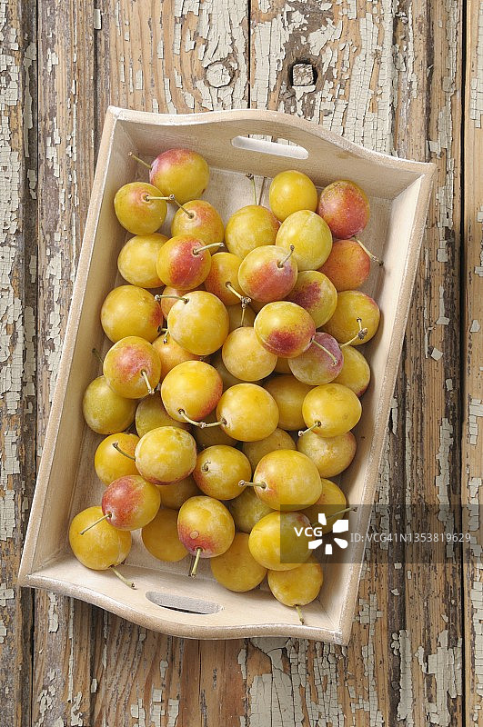 木托盘上的新鲜黄色李子图片素材