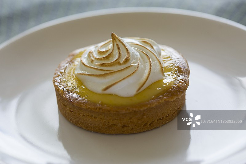 白色盘子上配蛋白酥皮的柠檬挞和杏仁皮图片素材