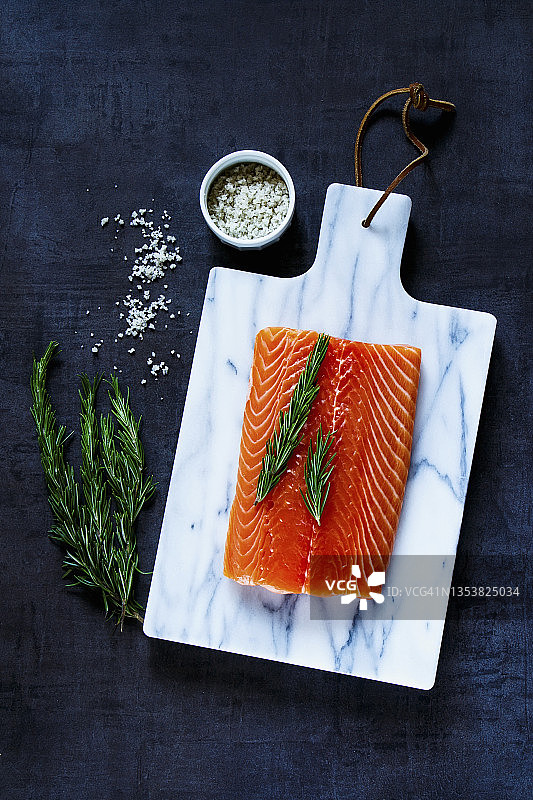 大理石砧板上的新鲜生鲑鱼片与迷迭香图片素材