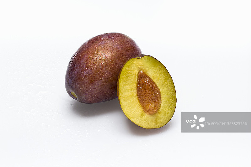 白色表面上的洋李和半个洋李图片素材