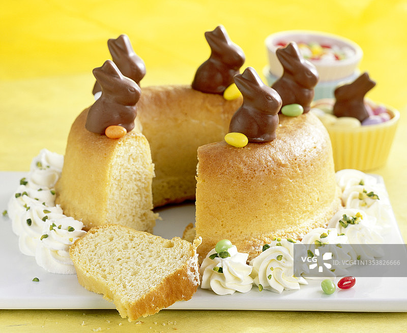 复活节萨瓦林蛋糕，配奶油、迷你巧克力兔子和彩色复活节彩蛋图片素材
